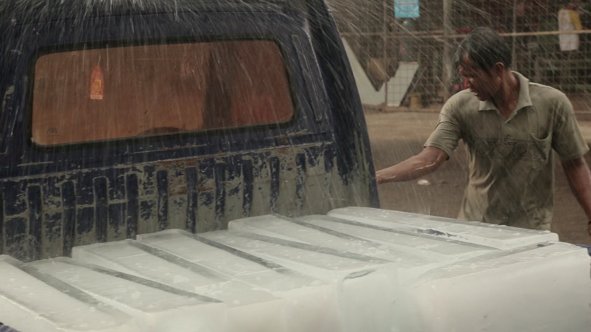 Auto met ijs in laadbak in de regen, man stapt in